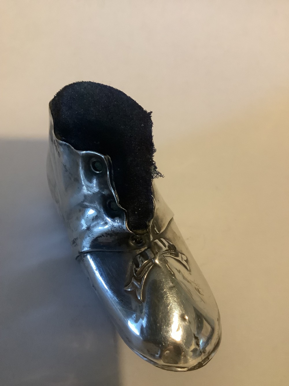 An antique silver pin cushion shaped like a laced boot with a dark velvet top insert. View VII