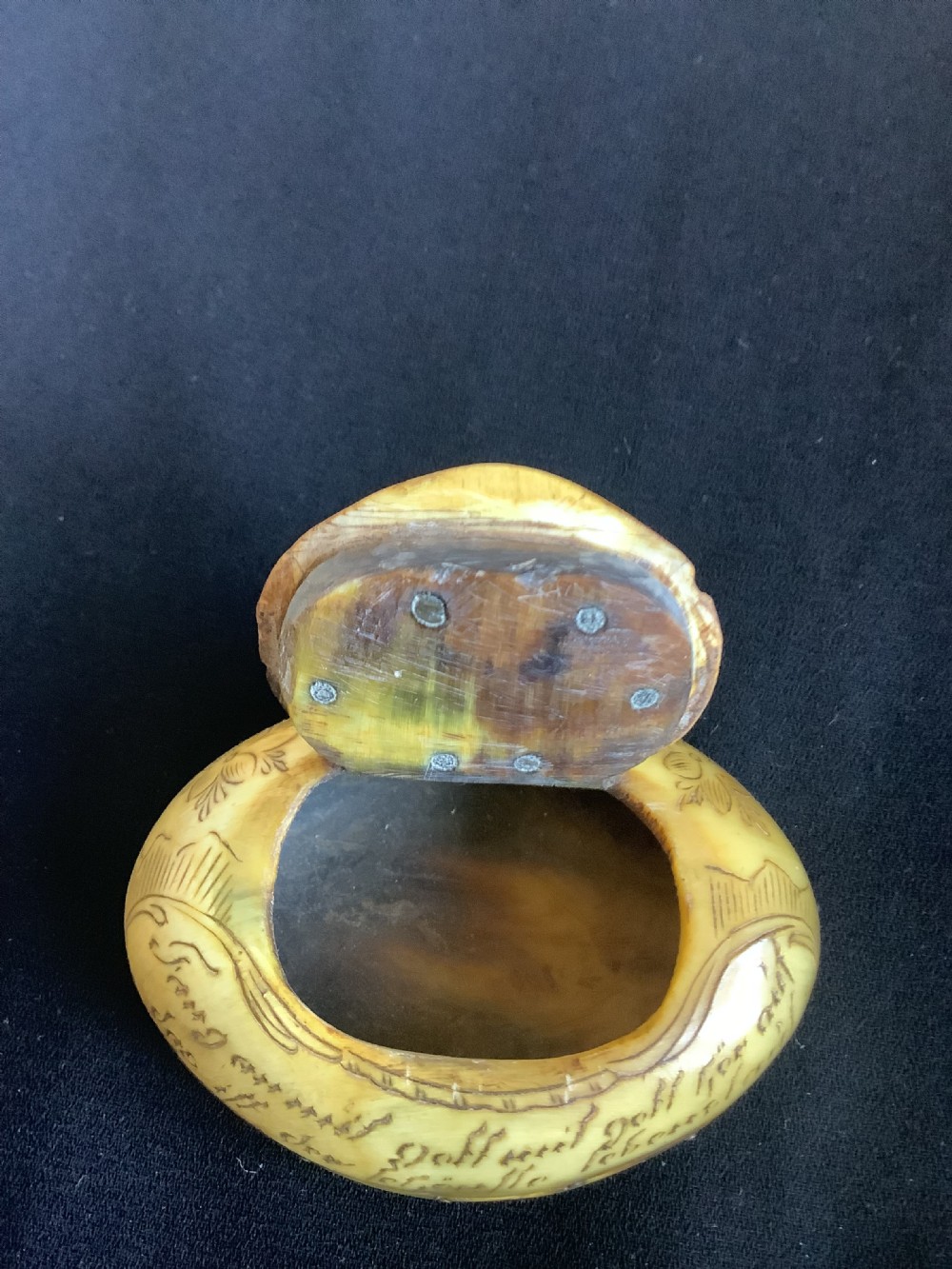 An oval antique horn pocket snuff box featuring hand-engraved depictions of Saint Joseph, floral motifs, and a central brass hinge. View IV