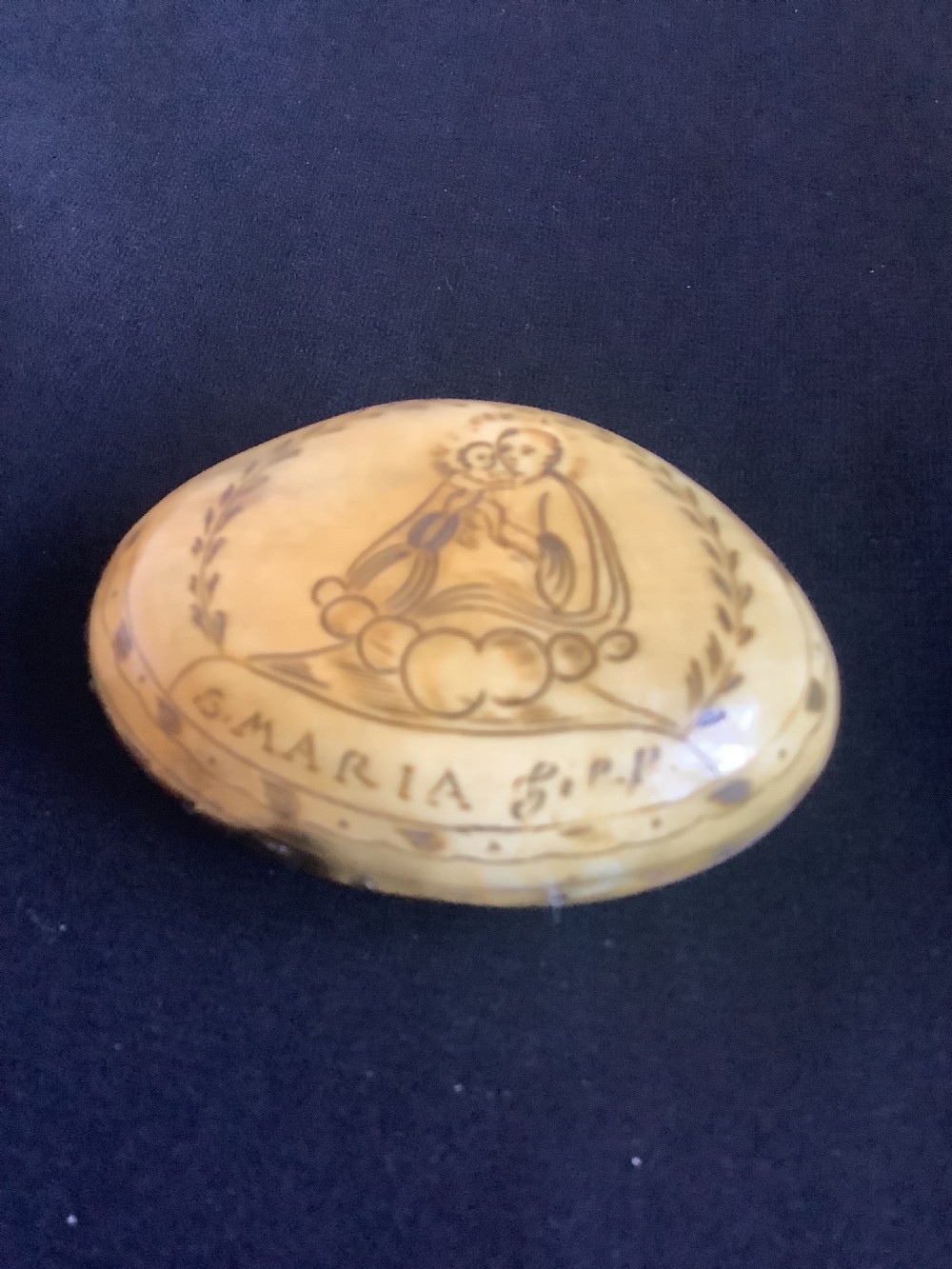 An oval antique horn pocket snuff box featuring hand-engraved depictions of Saint Joseph, floral motifs, and a central brass hinge. View V