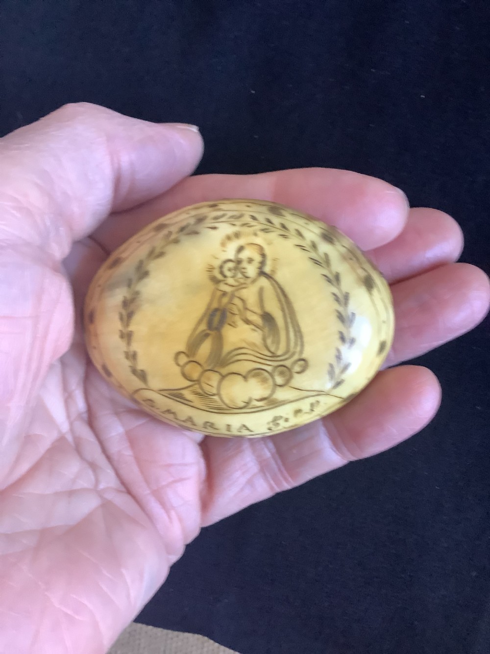 An oval antique horn pocket snuff box featuring hand-engraved depictions of Saint Joseph, floral motifs, and a central brass hinge. View VI