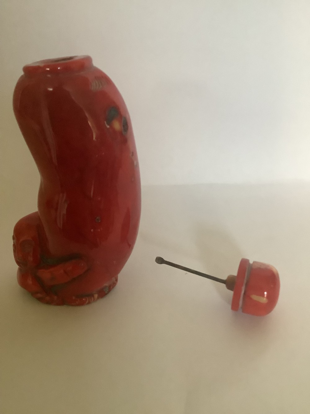 A carved bright red coral Chinese snuff bottle featuring an integrated carved figure at the base and a matching stopper. View III