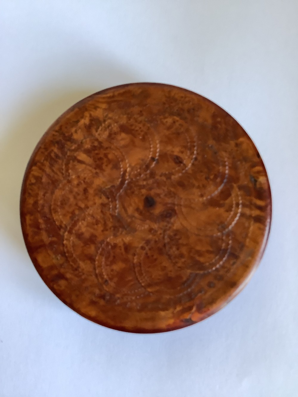 A circular carved burr walnut snuff box featuring segmented radial panels with relief figures and a central floral rosette. View VI