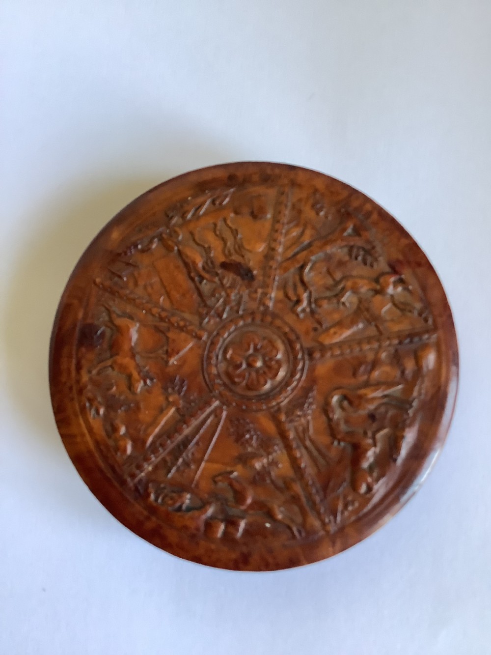 A circular carved burr walnut snuff box featuring segmented radial panels with relief figures and a central floral rosette. View VII