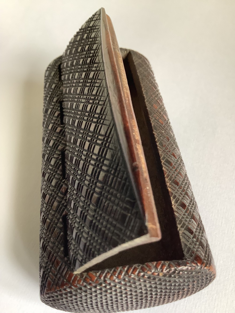 A small hand-carved dark hardwood snuff box featuring a detailed geometric lattice pattern held in a persons hand. View VII
