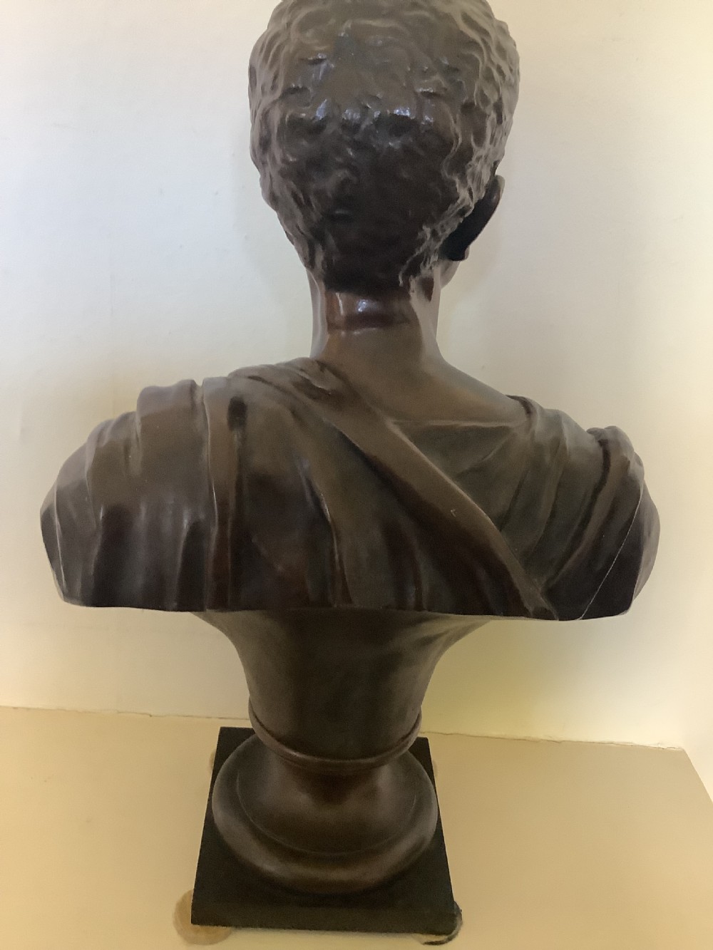 A patinated dark bronze bust depicting a classical Roman emperor with short curled hair and a draped toga, mounted on a turned circular socle and square base. View VIII