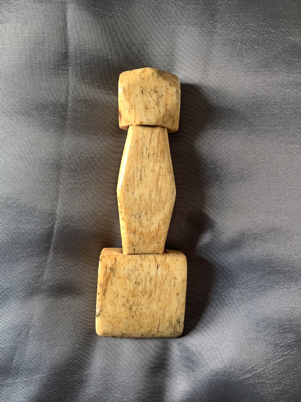 A hand-carved cream bone sailmakers seam rubber featuring a flattened blade base and a faceted geometric handle. View II