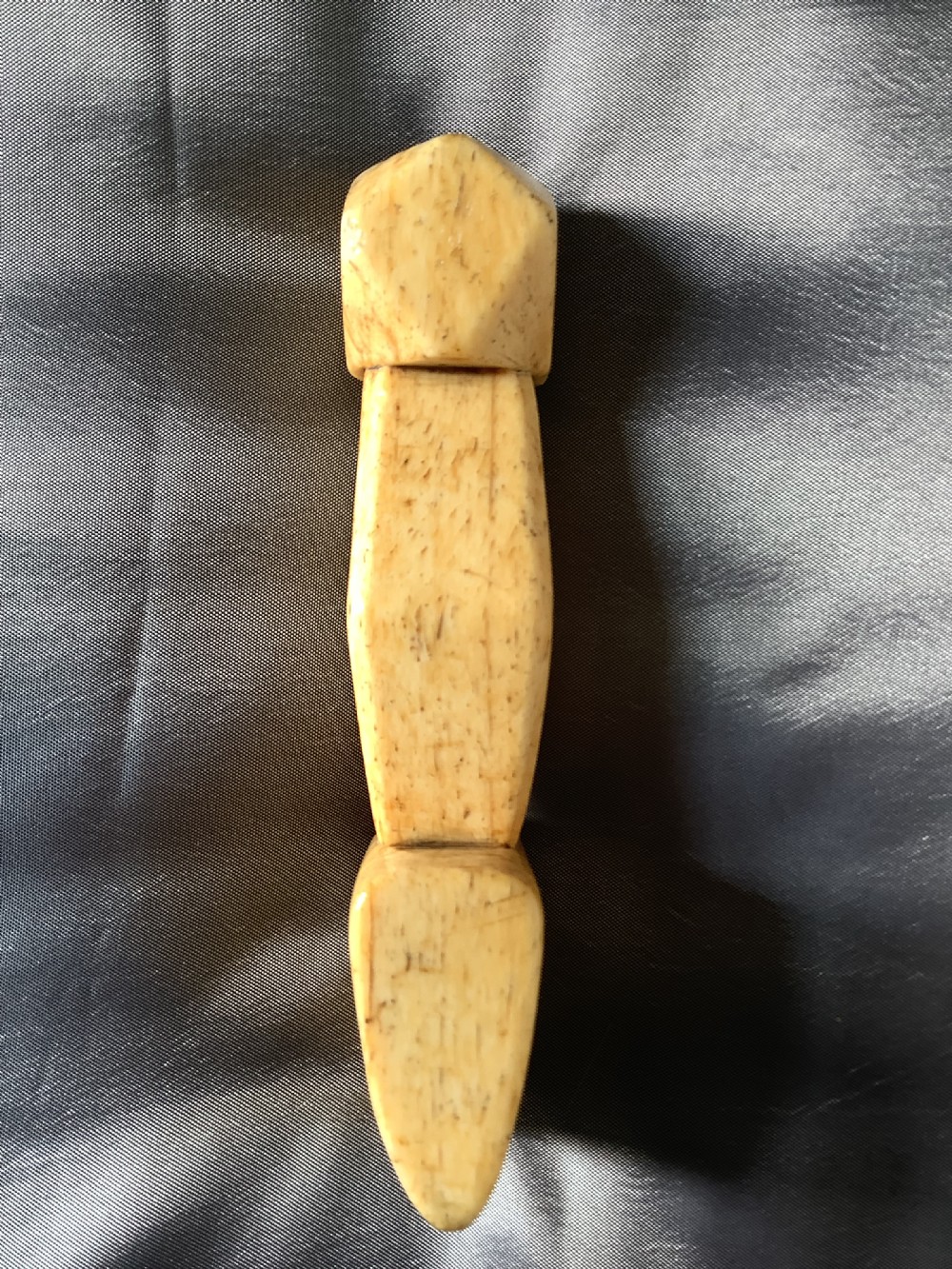 A hand-carved cream bone sailmakers seam rubber featuring a flattened blade base and a faceted geometric handle. View IV