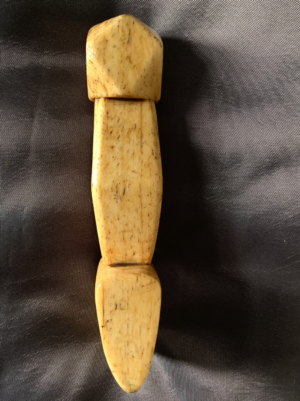 A hand-carved cream bone sailmakers seam rubber featuring a flattened blade base and a faceted geometric handle. View V