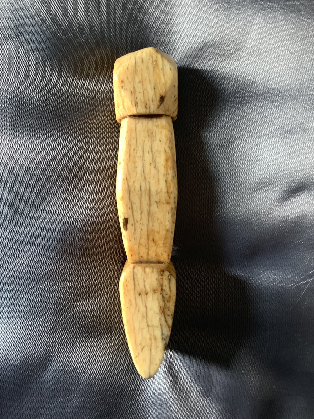 A hand-carved cream bone sailmakers seam rubber featuring a flattened blade base and a faceted geometric handle. View VI