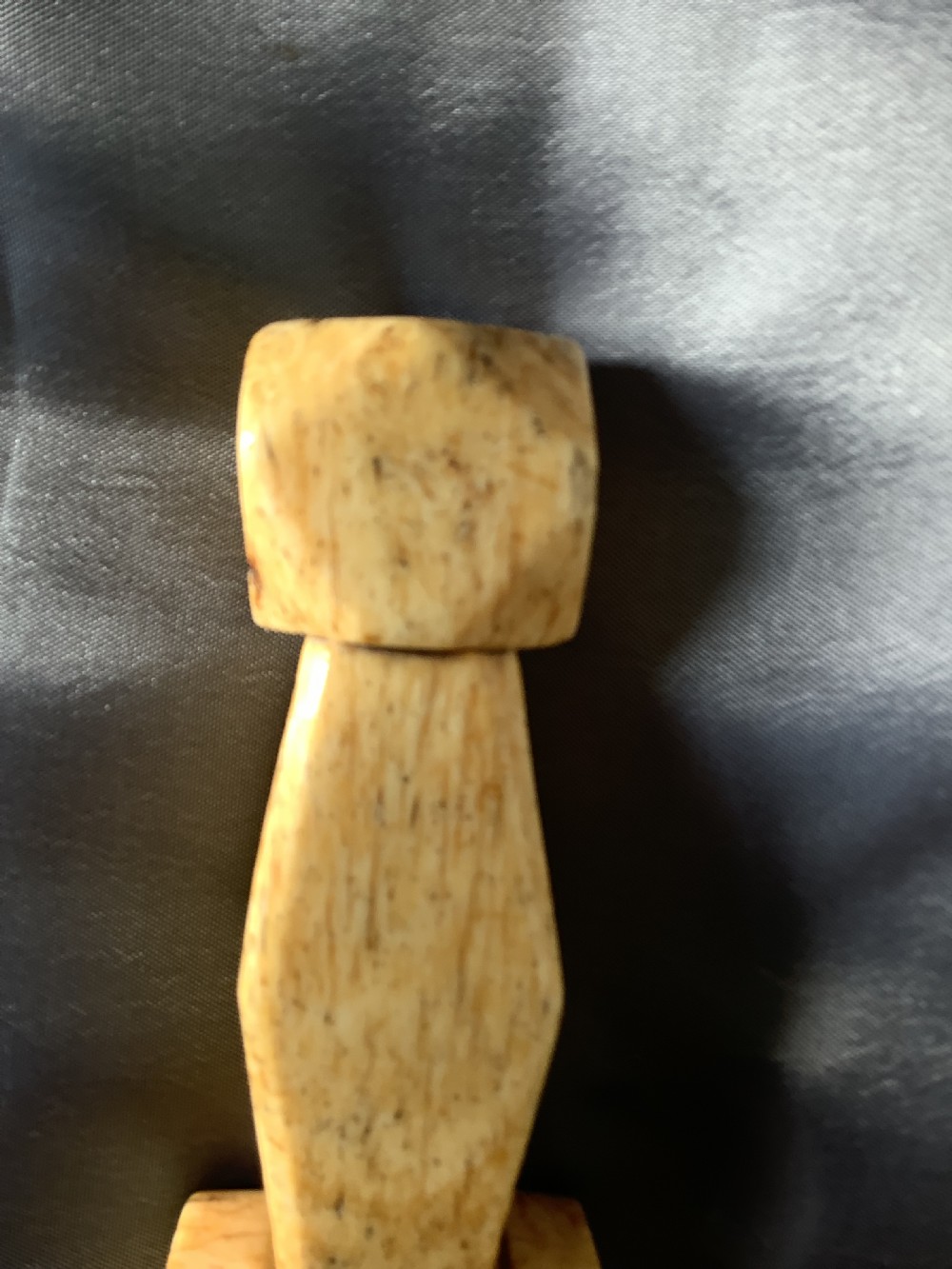 A hand-carved cream bone sailmakers seam rubber featuring a flattened blade base and a faceted geometric handle. View IX