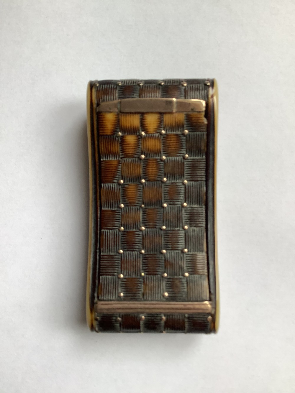 A rectangular carved horn snuff box featuring a basketweave surface pattern, metal pique studs, and subtly curved sides.