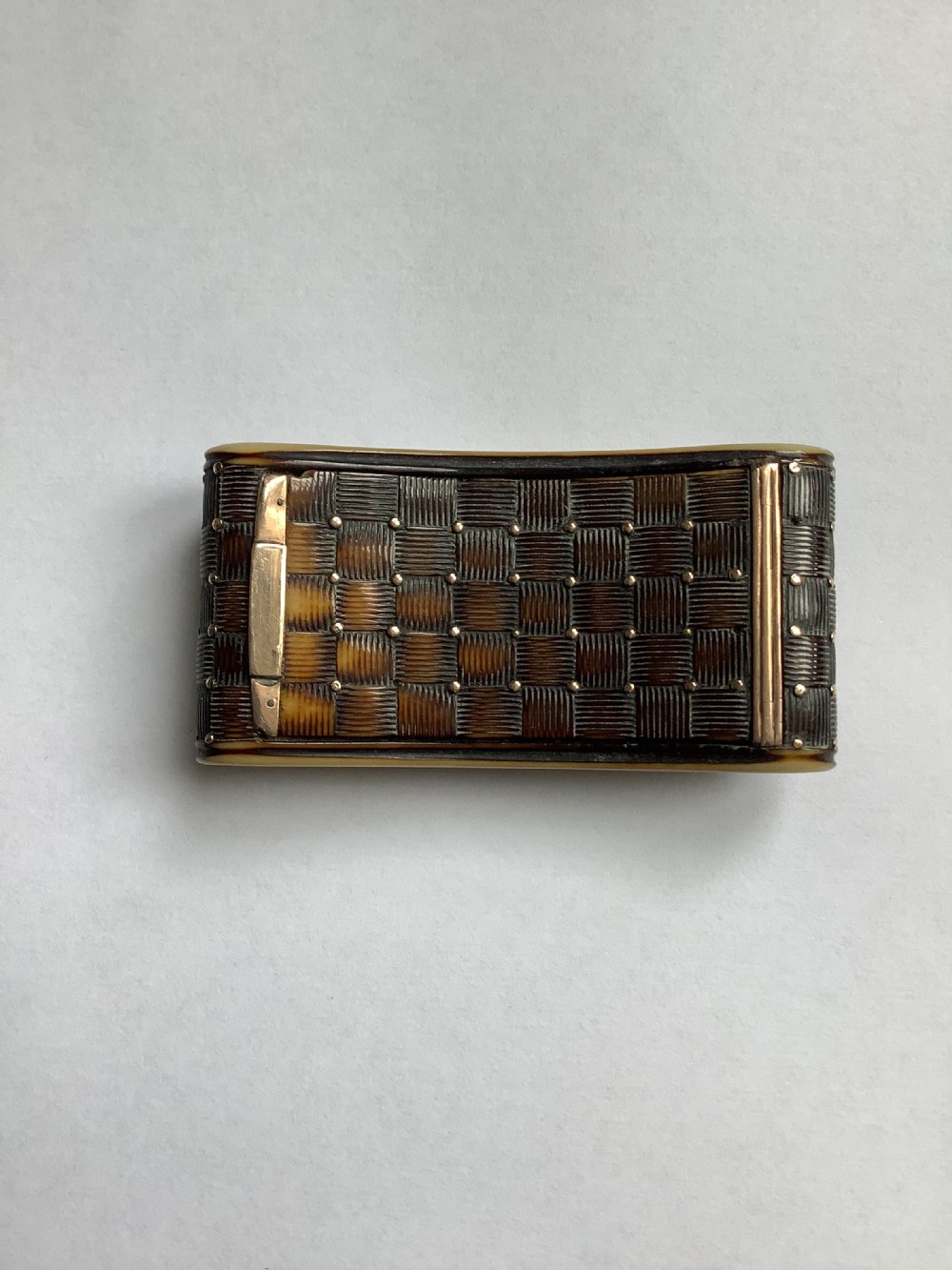 A rectangular carved horn snuff box featuring a basketweave surface pattern, metal pique studs, and subtly curved sides. View II