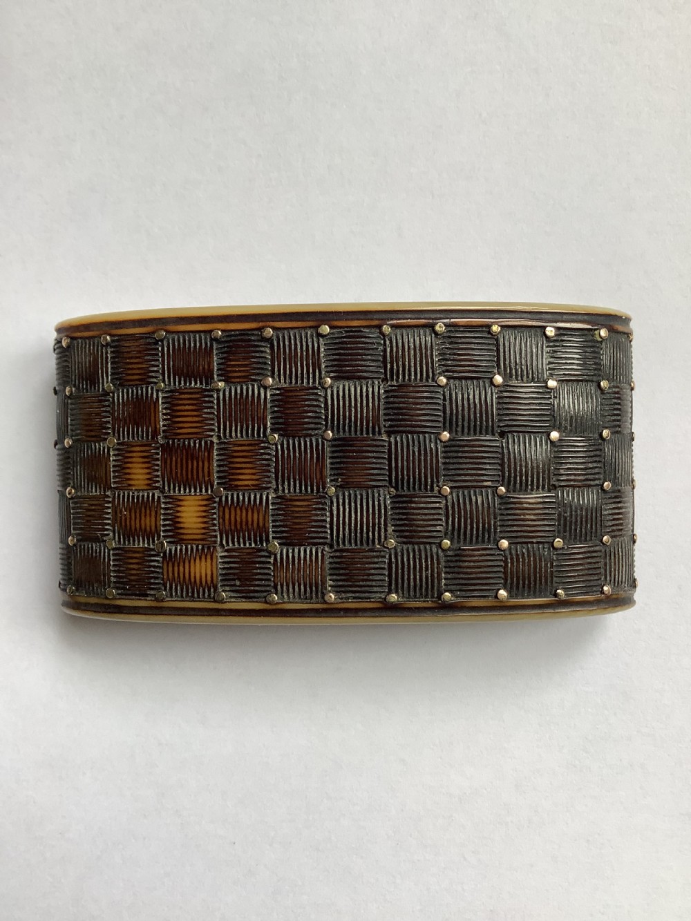A rectangular carved horn snuff box featuring a basketweave surface pattern, metal pique studs, and subtly curved sides. View III