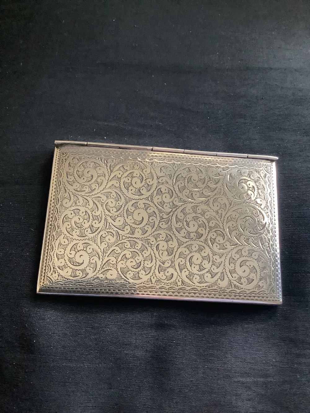 An Edwardian sterling silver card case designed in the shape of an envelope with detailed foliate engraving and a central monogram. View III