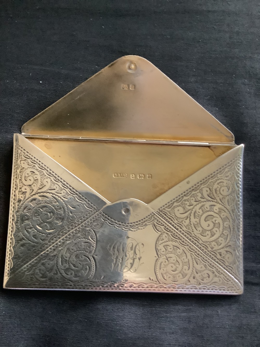 An Edwardian sterling silver card case designed in the shape of an envelope with detailed foliate engraving and a central monogram. View IV