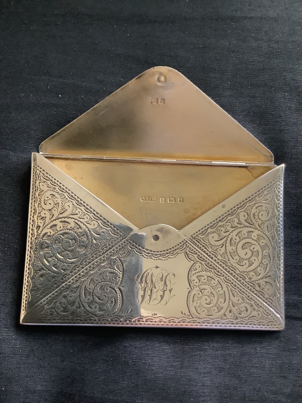 An Edwardian sterling silver card case designed in the shape of an envelope with detailed foliate engraving and a central monogram. View VI