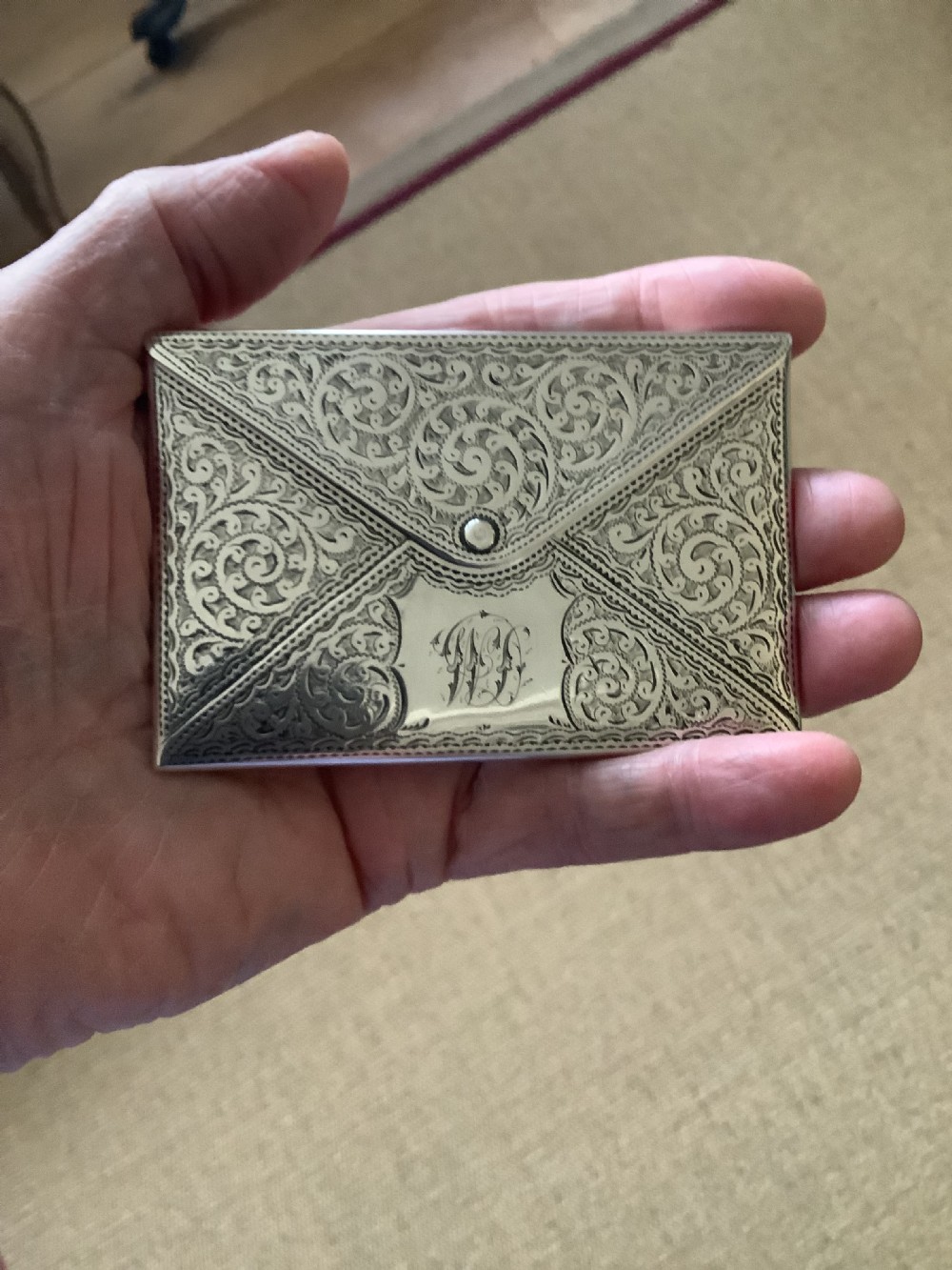 An Edwardian sterling silver card case designed in the shape of an envelope with detailed foliate engraving and a central monogram. View VII