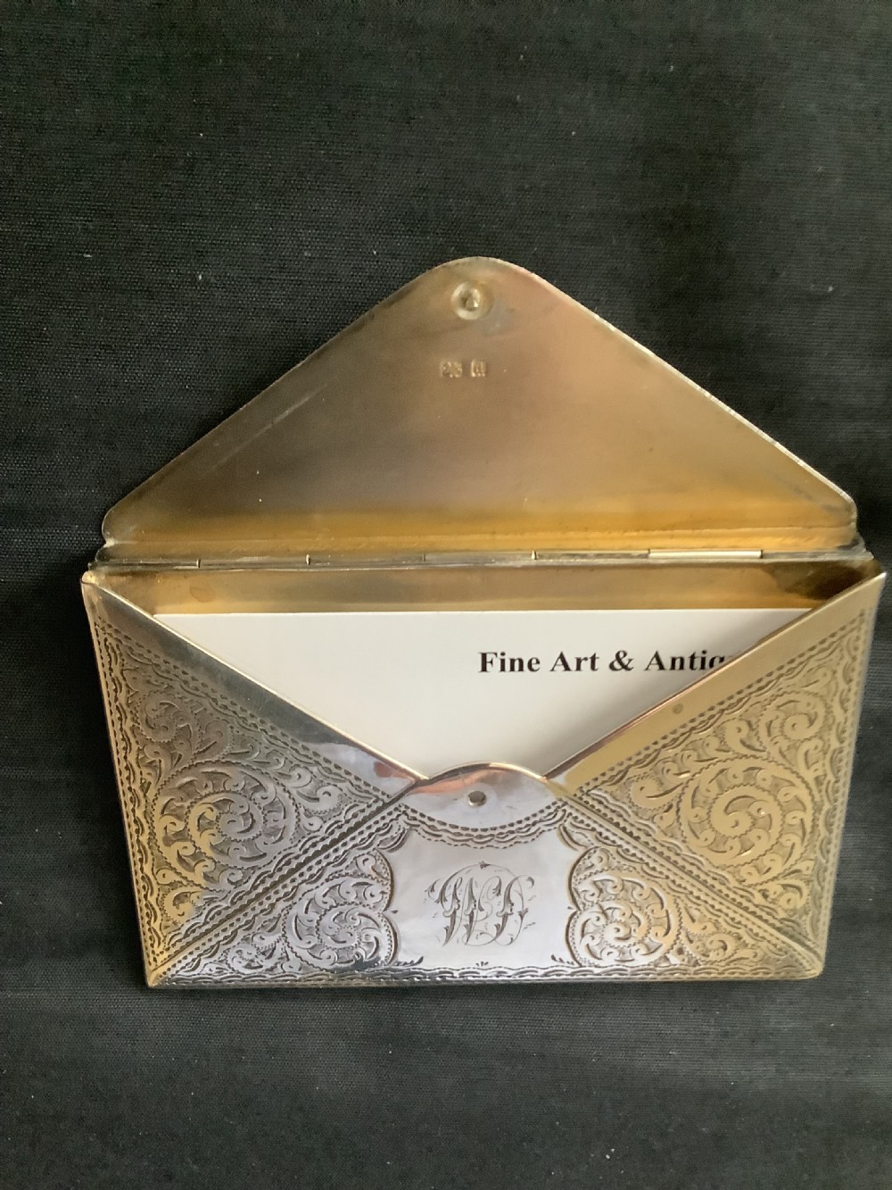 An Edwardian sterling silver card case designed in the shape of an envelope with detailed foliate engraving and a central monogram. View VIII