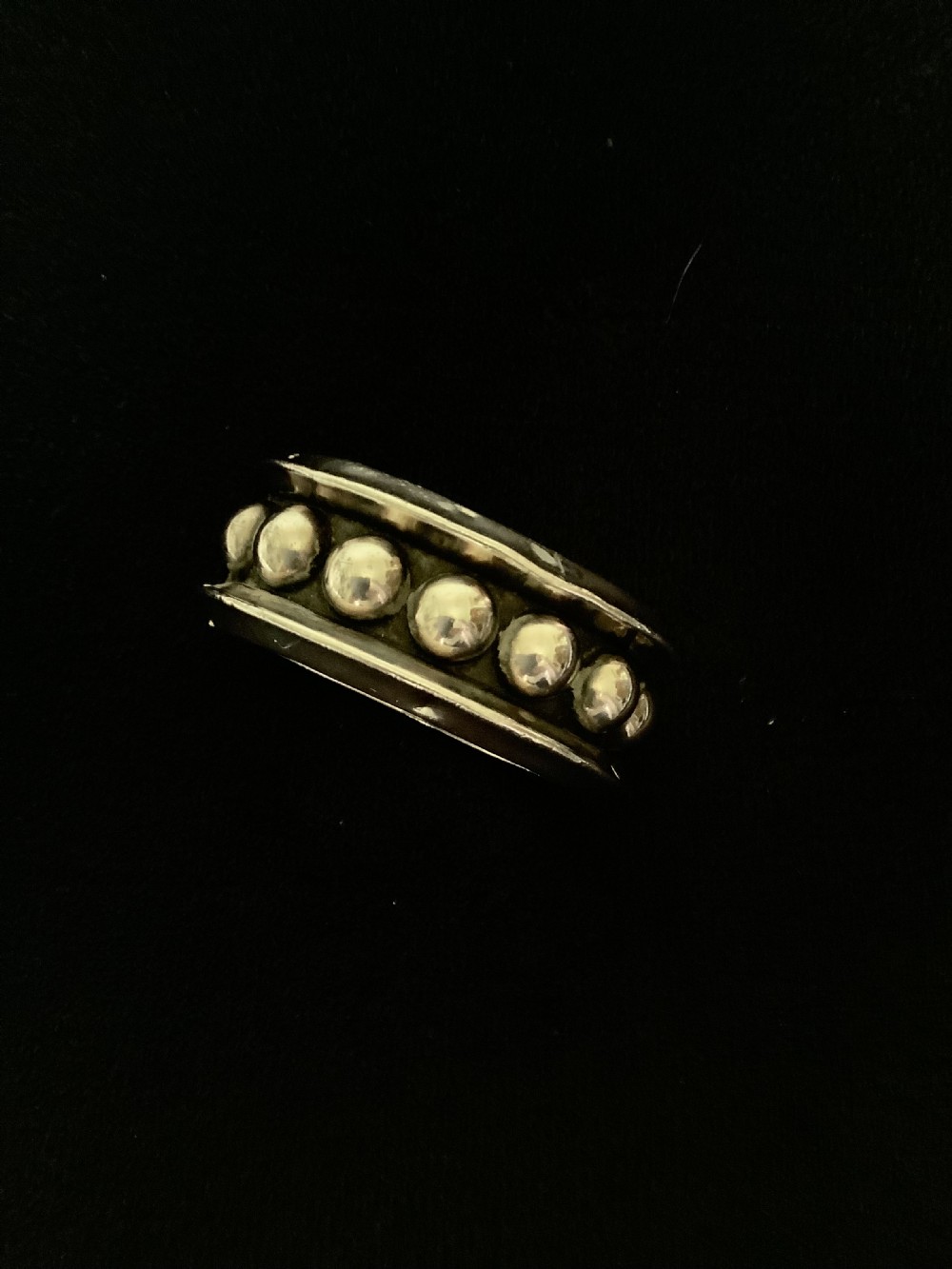 A wide sterling silver cuff bracelet featuring a central row of raised spherical studs bordered by raised outer rims. View VI