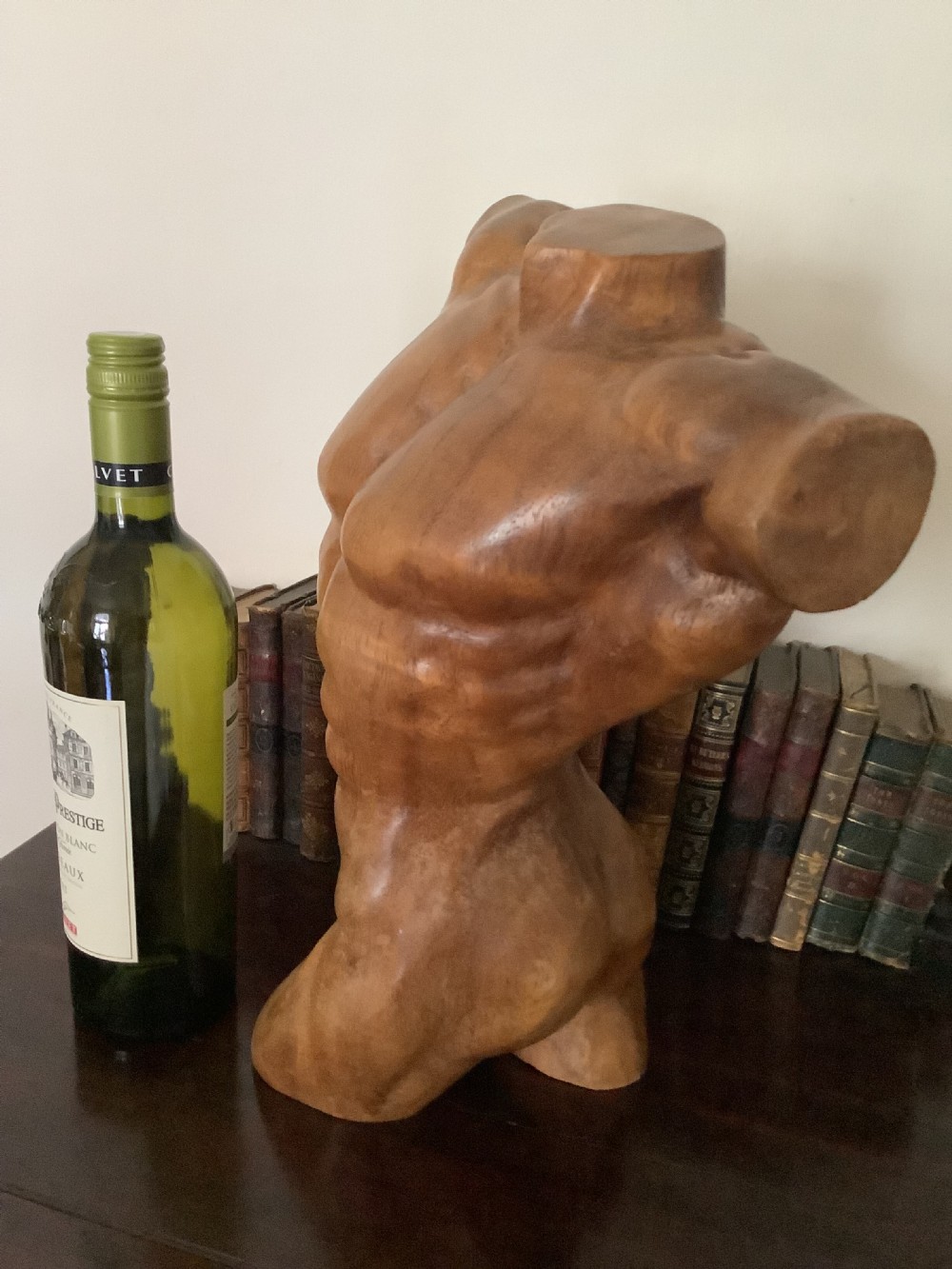 A three-dimensional carved hardwood sculpture depicting a classical male torso with defined muscle structure and a smooth polished finish. View II