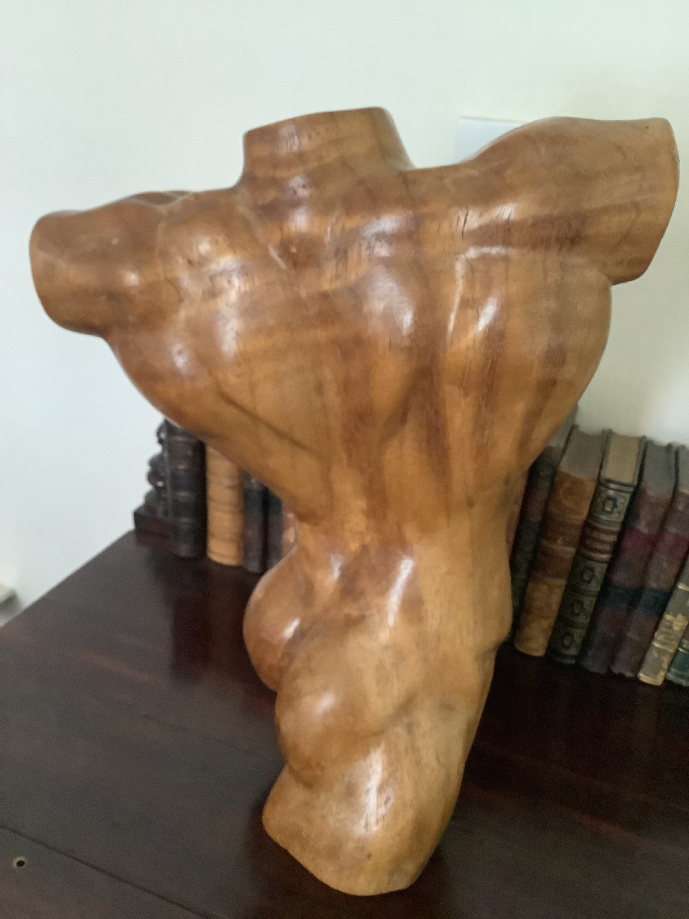 A three-dimensional carved hardwood sculpture depicting a classical male torso with defined muscle structure and a smooth polished finish. View VII