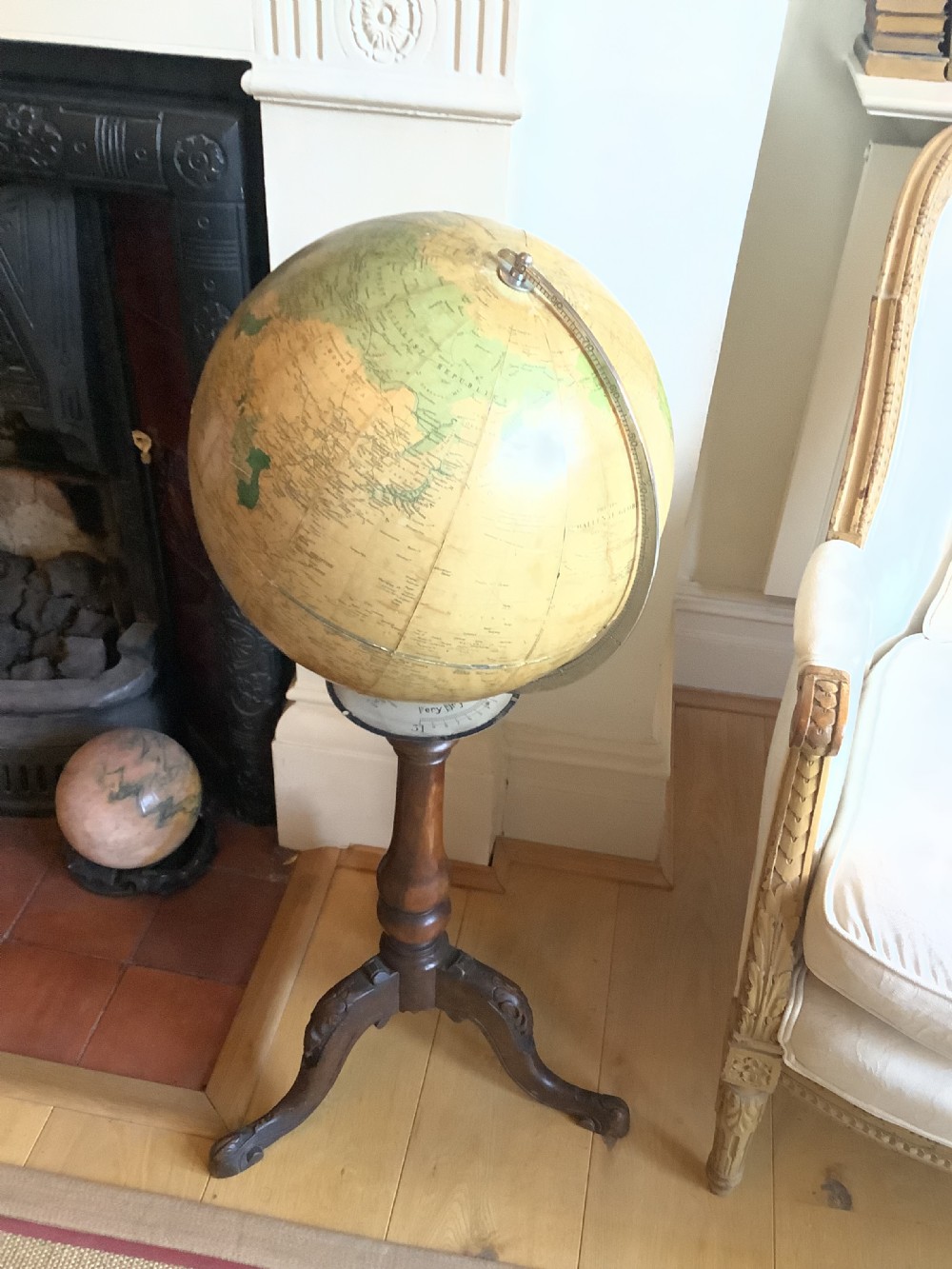 A terrestrial floor-standing globe mounted on a brass half-meridian, supported by a turned mahogany column with carved tripod cabriole legs. View IV