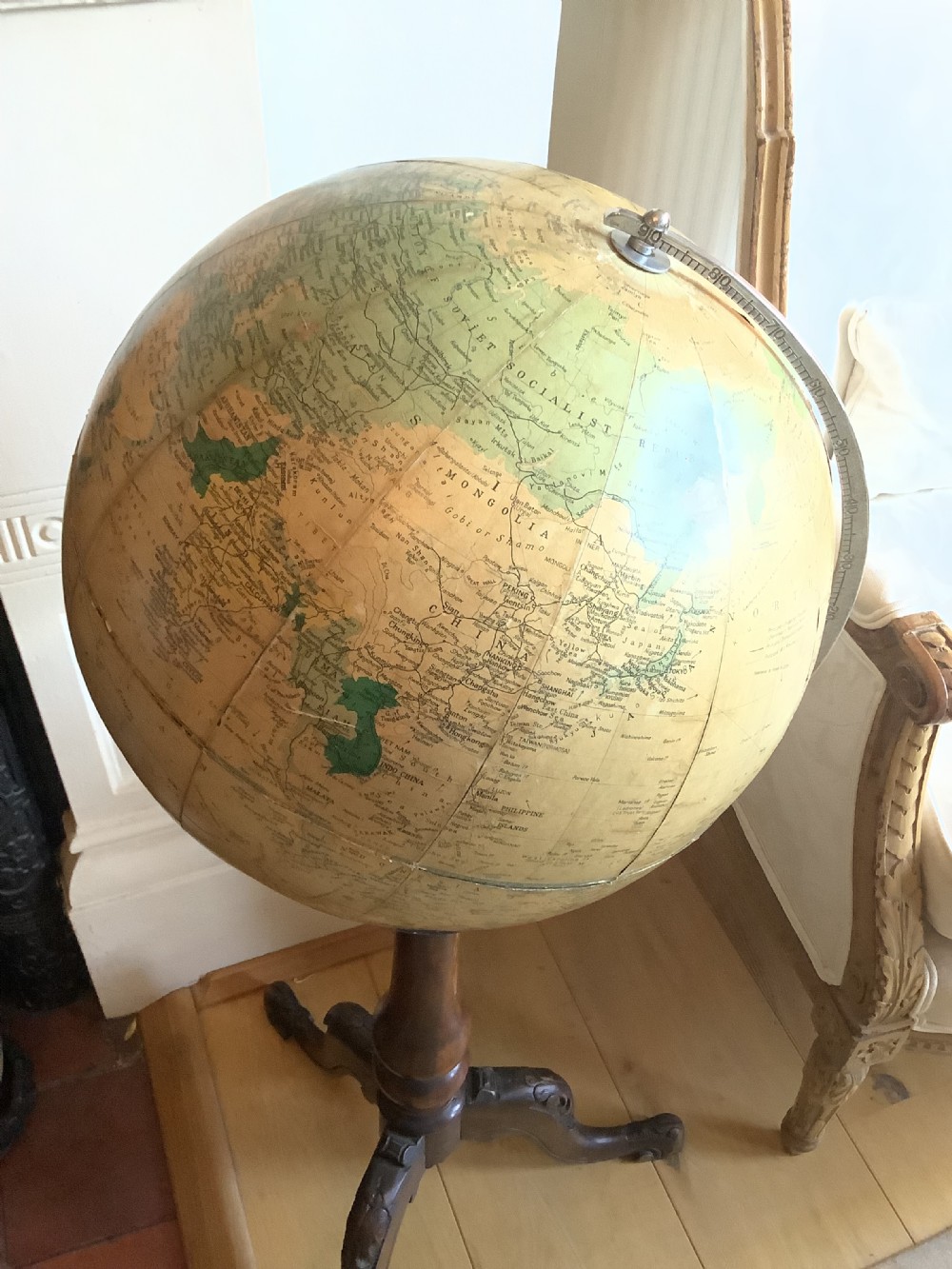 A terrestrial floor-standing globe mounted on a brass half-meridian, supported by a turned mahogany column with carved tripod cabriole legs. View V