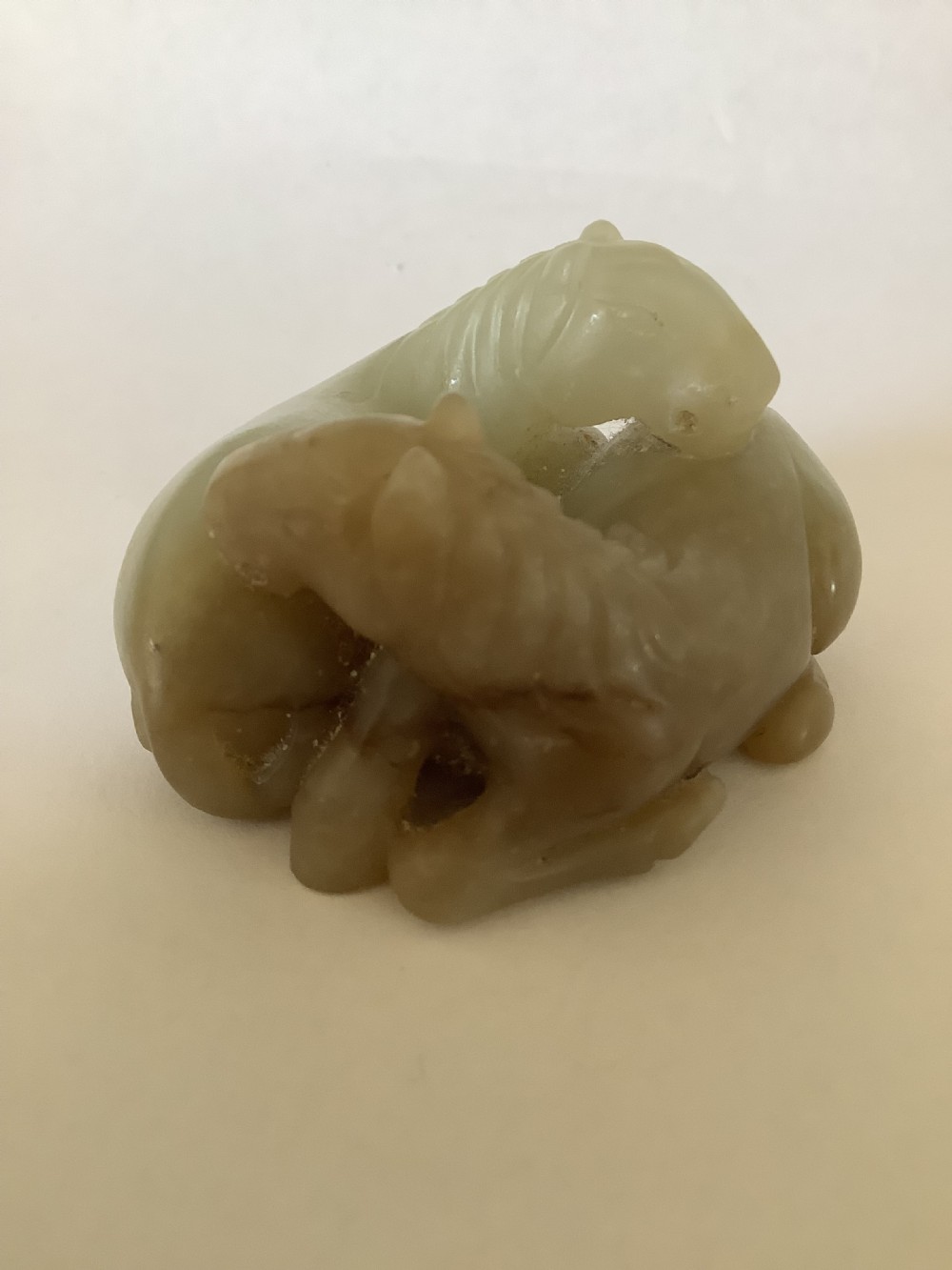 A small 19th-century Chinese hand-carved jade sculpture depicting two intertwined recumbent horses in pale celadon green and grey hardstone. View IV