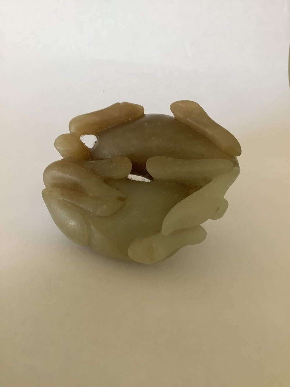 A small 19th-century Chinese hand-carved jade sculpture depicting two intertwined recumbent horses in pale celadon green and grey hardstone. View V