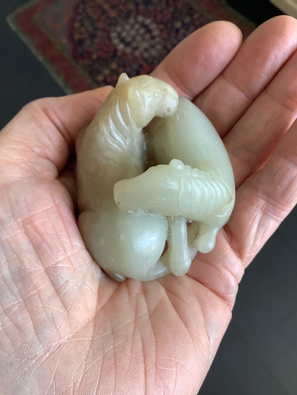 A small 19th-century Chinese hand-carved jade sculpture depicting two intertwined recumbent horses in pale celadon green and grey hardstone. View VI