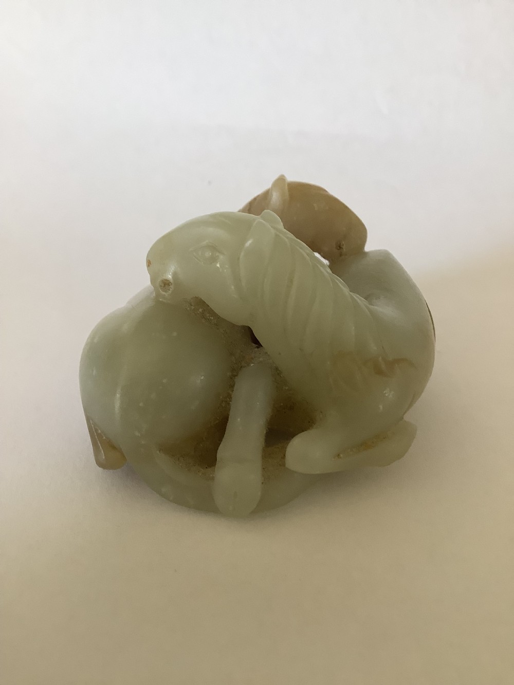 A small 19th-century Chinese hand-carved jade sculpture depicting two intertwined recumbent horses in pale celadon green and grey hardstone. View VII