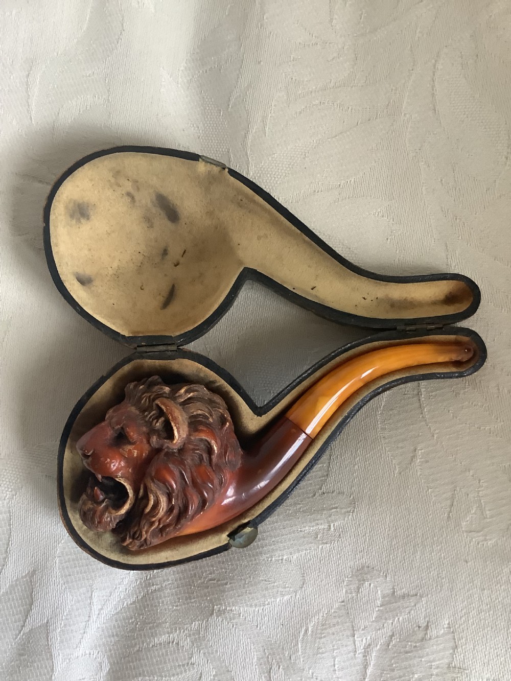 A hand-carved meerschaum smoking pipe featuring a detailed lion head bowl with an open mouth and a translucent amber-coloured curved stem. View III