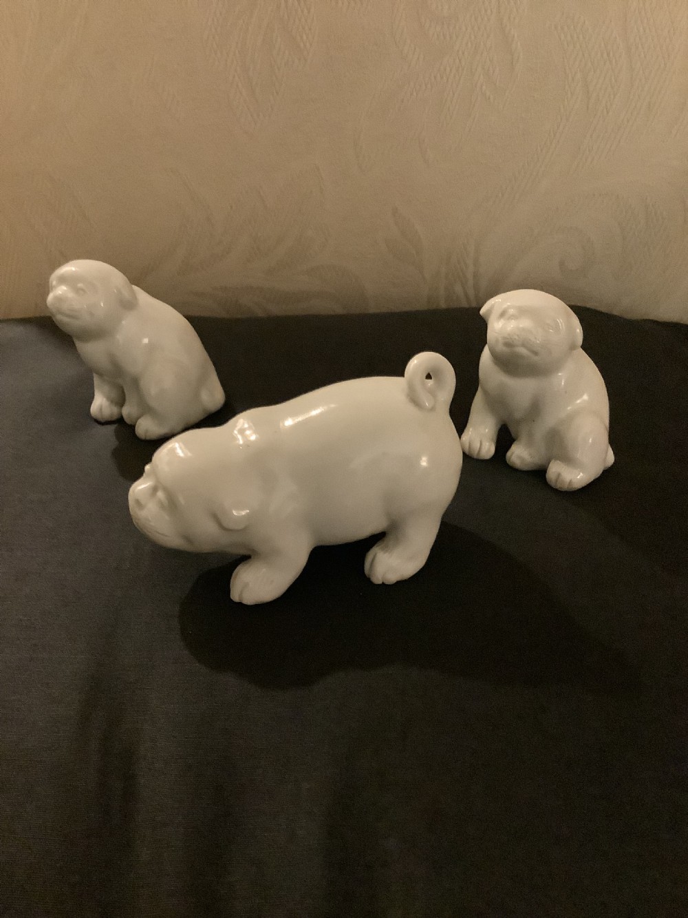 A set of three monochrome white glazed porcelain Japanese Hirado puppy figurines sculpted in seated and standing poses.