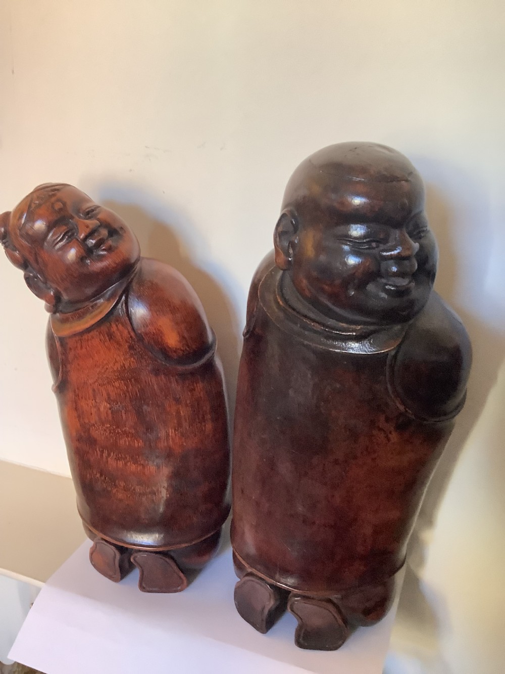 A pair of carved brown bamboo headrests depicted as rounded smiling figures with smooth polished surfaces.