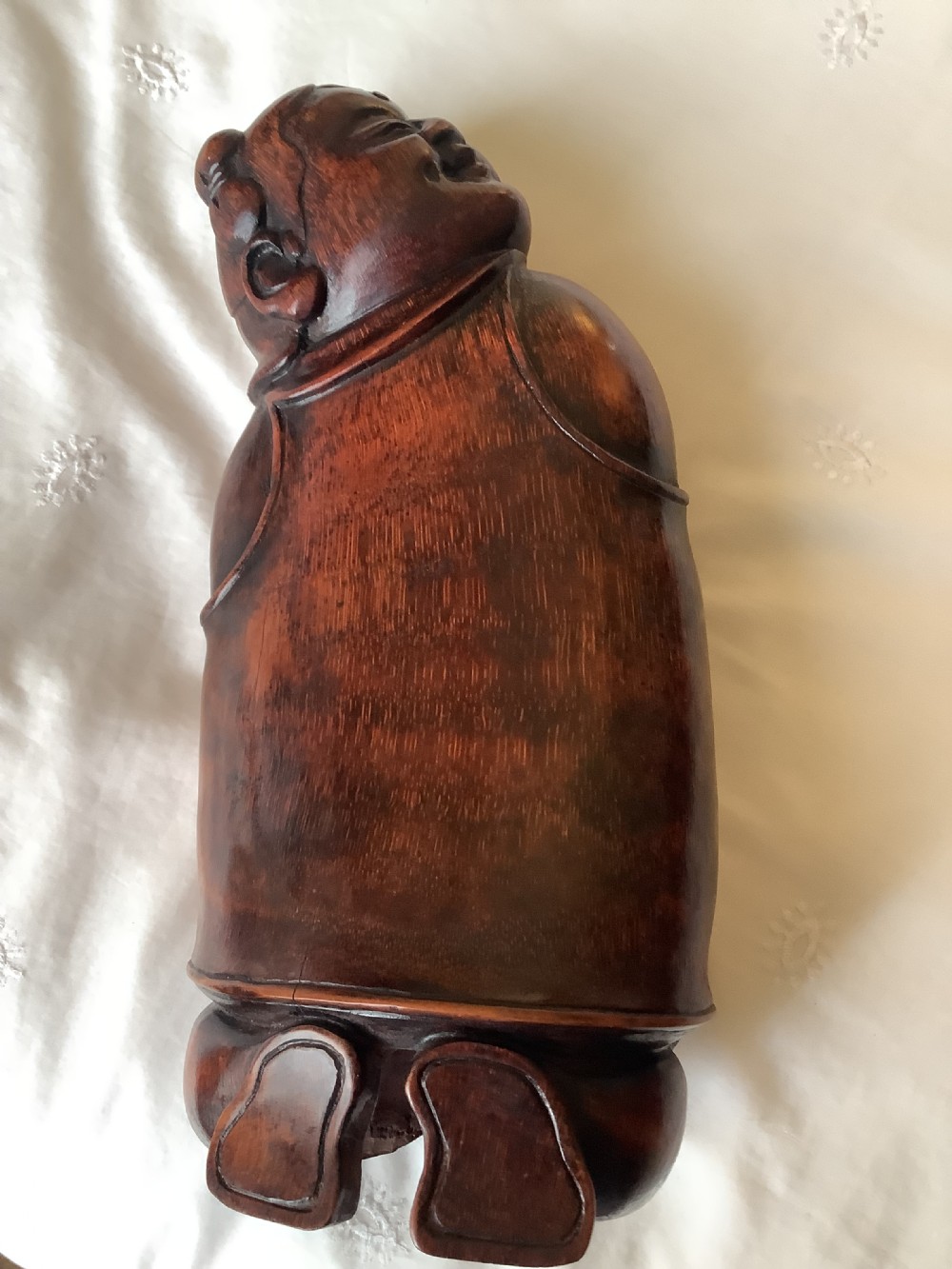 A pair of carved brown bamboo headrests depicted as rounded smiling figures with smooth polished surfaces. View III