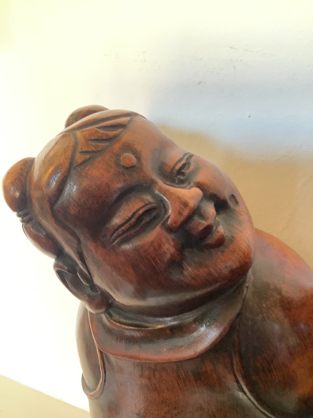 A pair of carved brown bamboo headrests depicted as rounded smiling figures with smooth polished surfaces. View IV