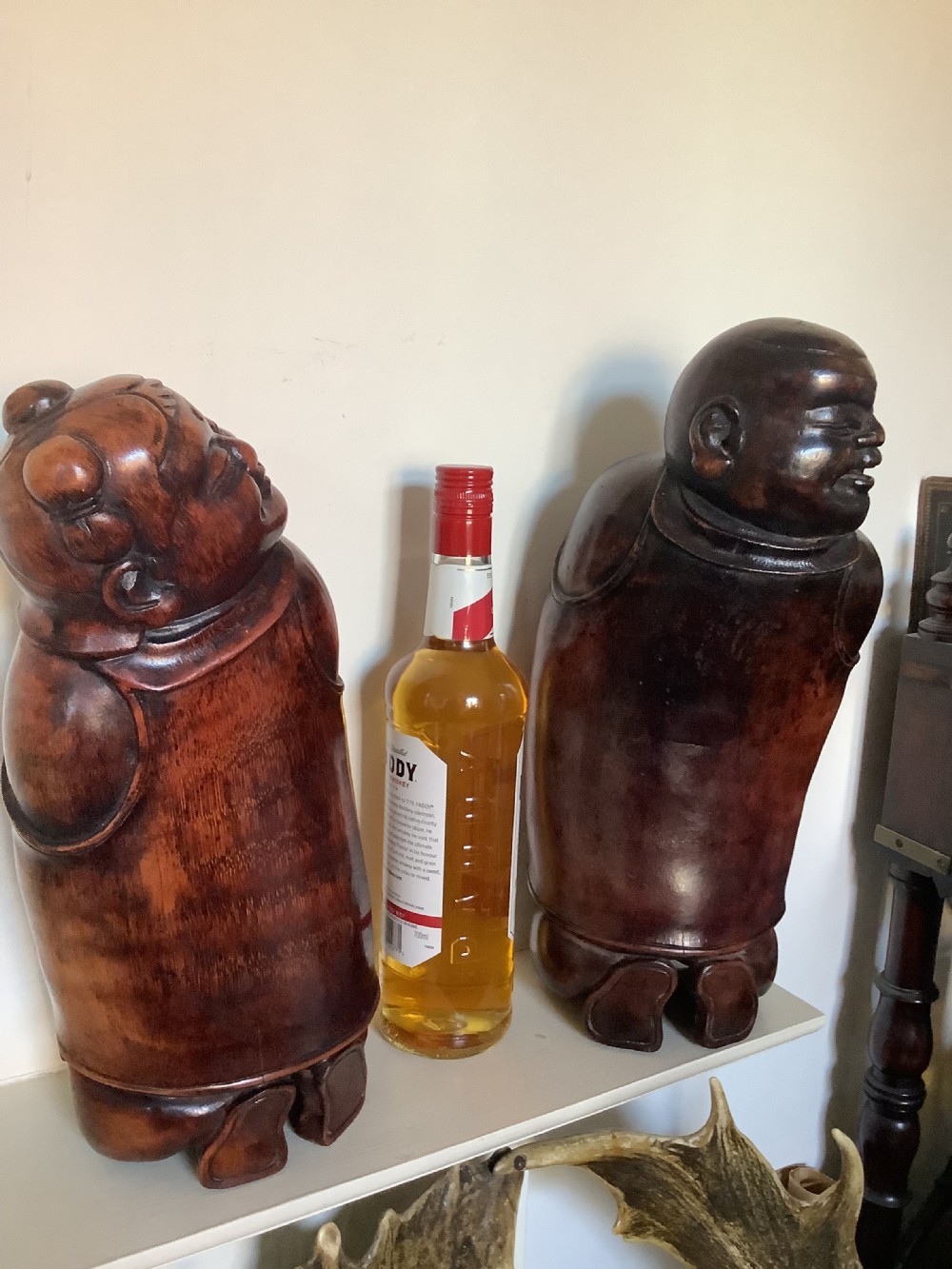 A pair of carved brown bamboo headrests depicted as rounded smiling figures with smooth polished surfaces. View V
