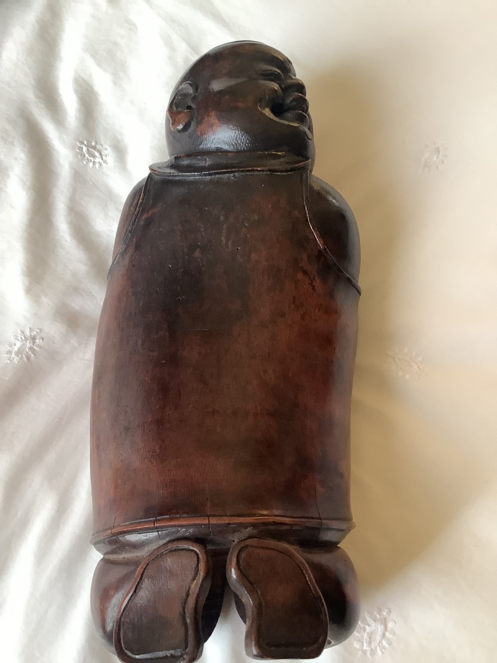 A pair of carved brown bamboo headrests depicted as rounded smiling figures with smooth polished surfaces. View VII