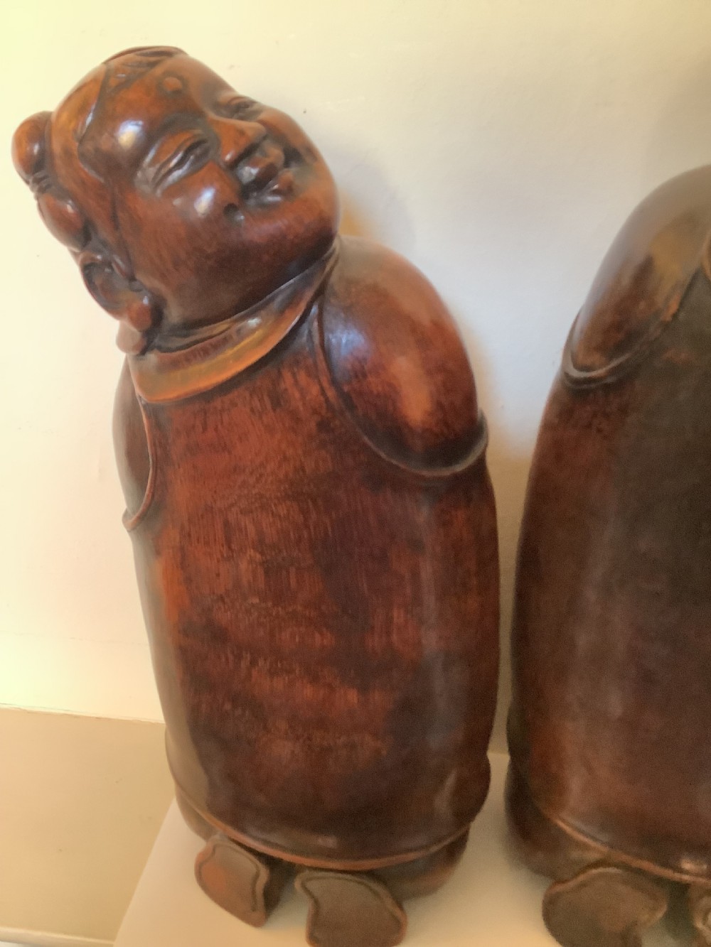 A pair of carved brown bamboo headrests depicted as rounded smiling figures with smooth polished surfaces. View VIII