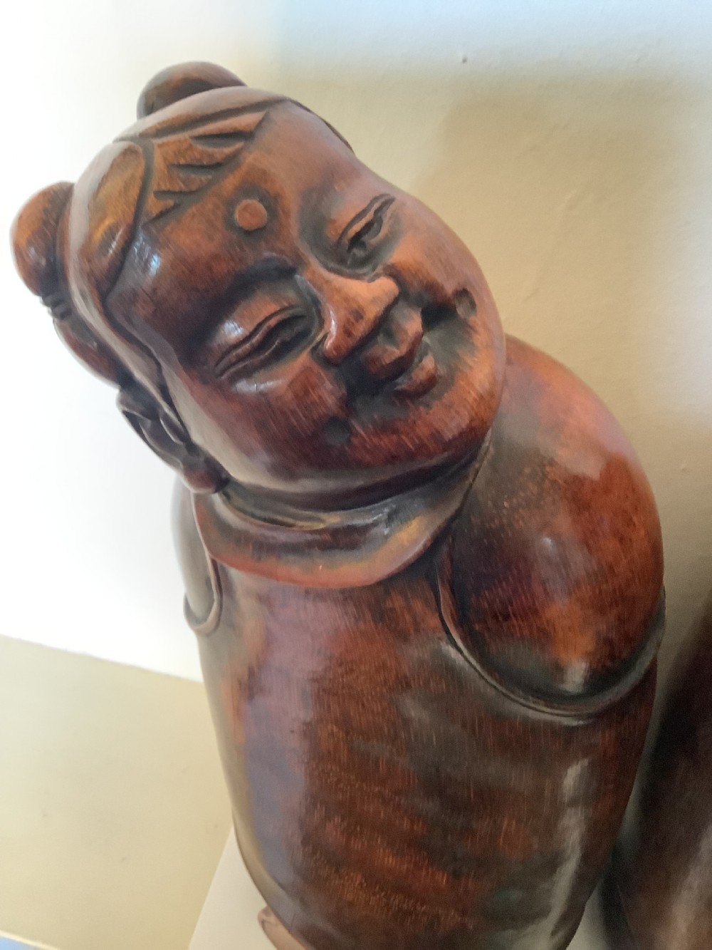 A pair of carved brown bamboo headrests depicted as rounded smiling figures with smooth polished surfaces. View IX