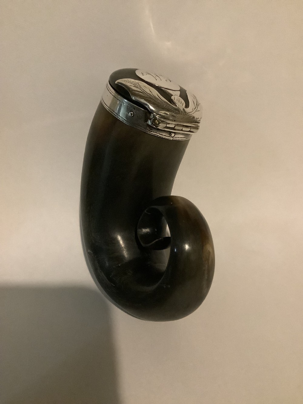 An early nineteenth-century Scottish snuff mull crafted from polished dark horn with a curled tip and an engraved silver hinged lid.