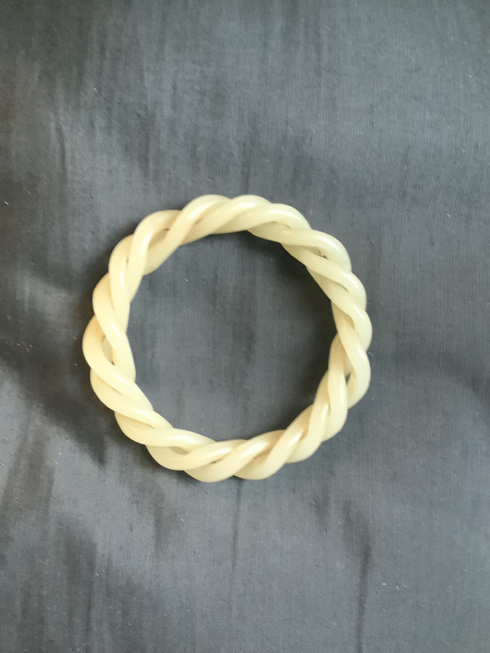 An off-white carved jade bangle featuring a continuous twisted rope design crafted from a single piece of stone. View V