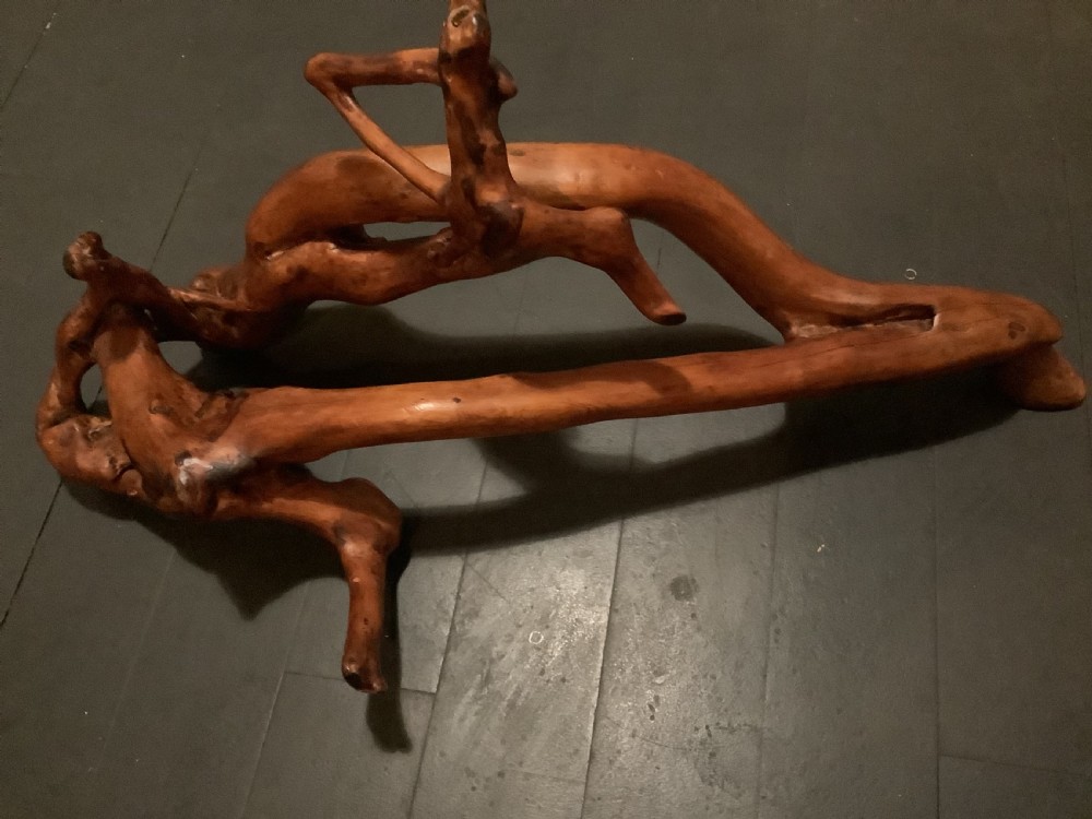 A polished yew wood sculpture featuring organic, intertwined smooth branches with a rich golden-amber tone.