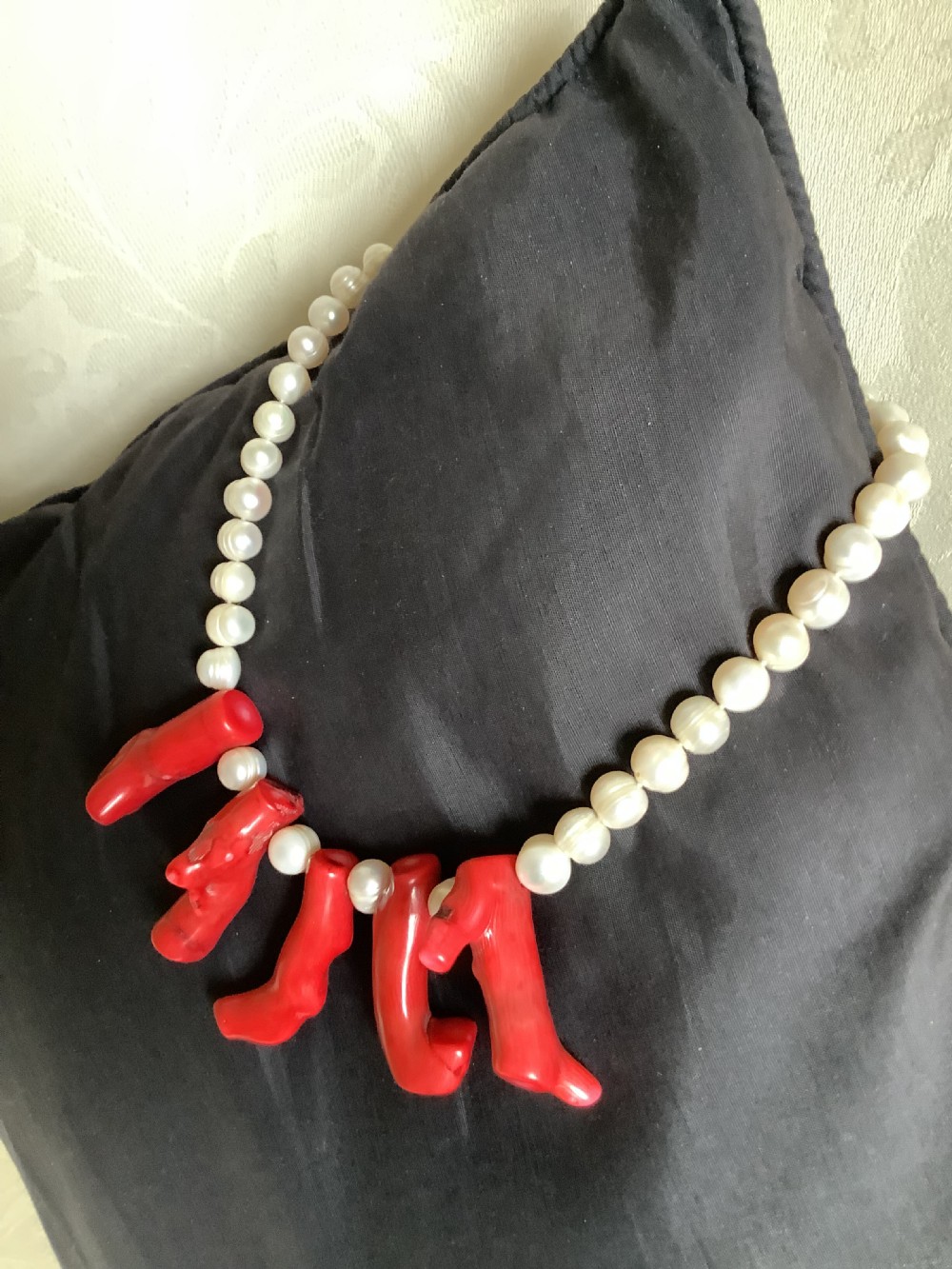A necklace featuring a strand of rounded white pearls accented by five suspended polished red coral branches at the front centre. View III