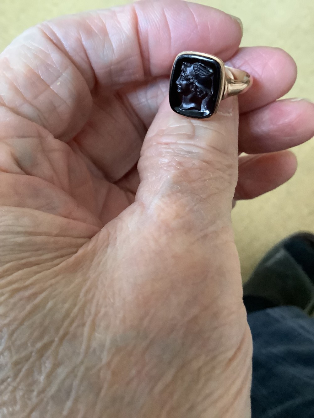 A gold ring set with a cushion-shaped dark gemstone featuring an intaglio-carved classical profile portrait. View IV