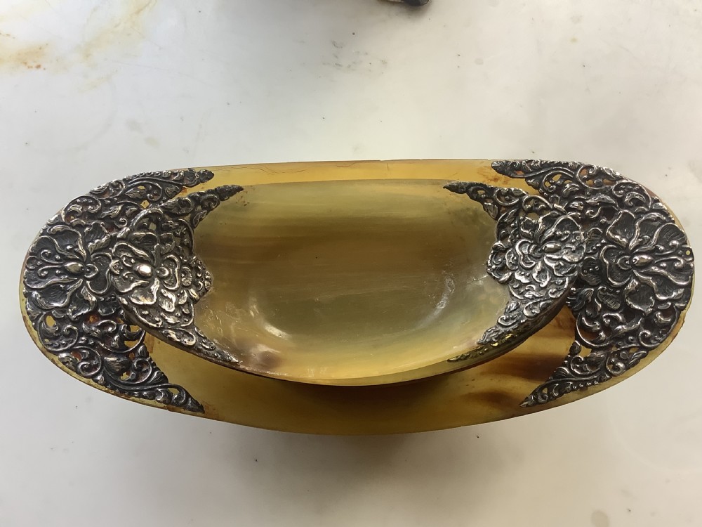 A set of seven oval amber-toned horn bowls featuring carved floral silver mounts at each end. View VIII