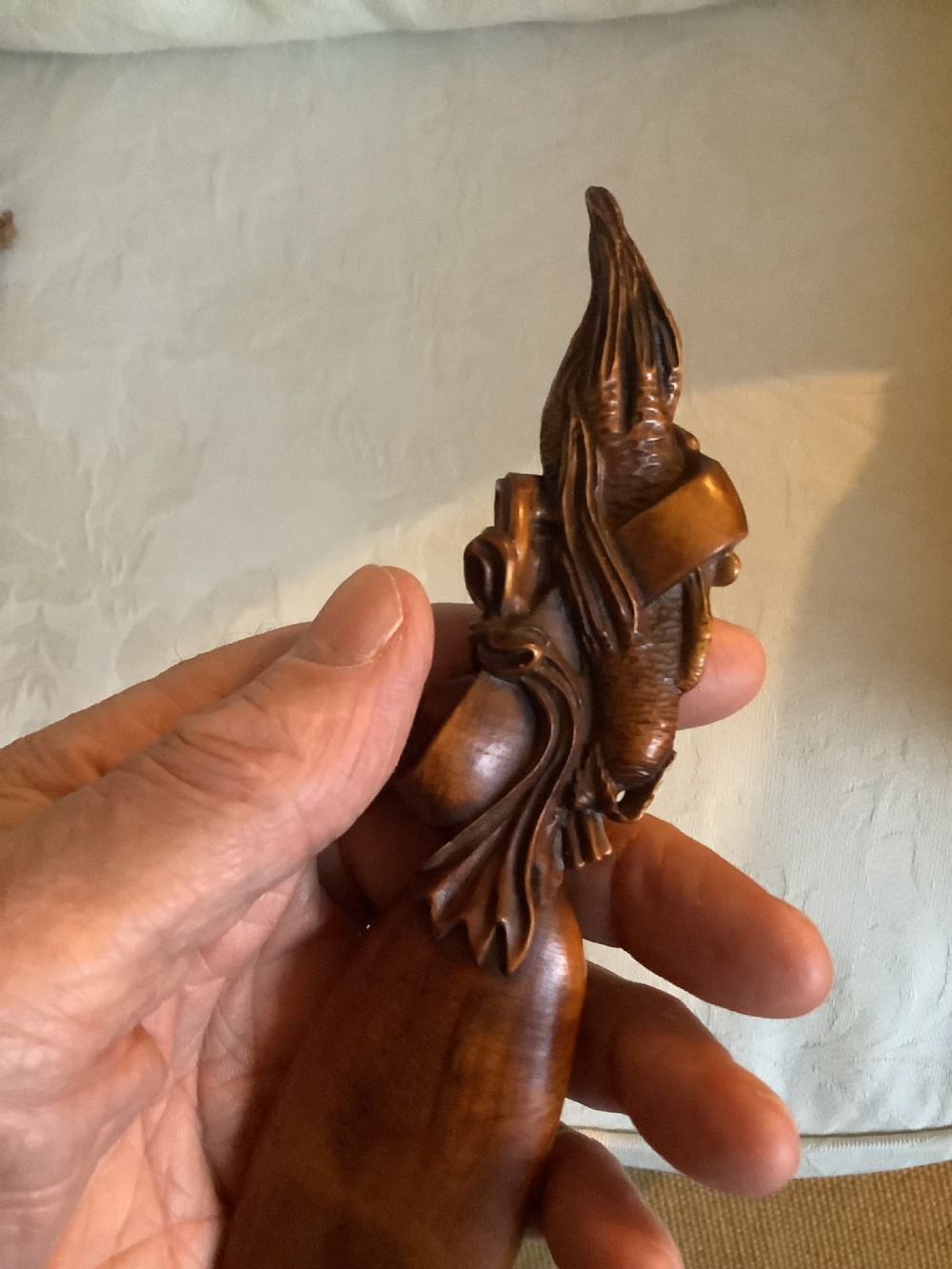 A hand-carved warm brown hardwood tea scoop featuring detailed figurative relief work along the upper handle. View VI