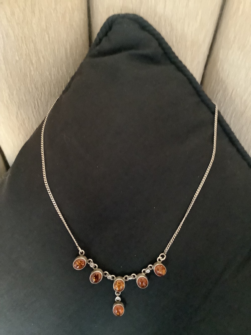 A fine silver chain necklace featuring six bezel-set oval cognac amber cabochons arranged in a central drop configuration.