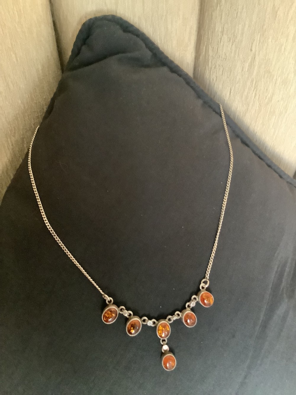 A fine silver chain necklace featuring six bezel-set oval cognac amber cabochons arranged in a central drop configuration. View II
