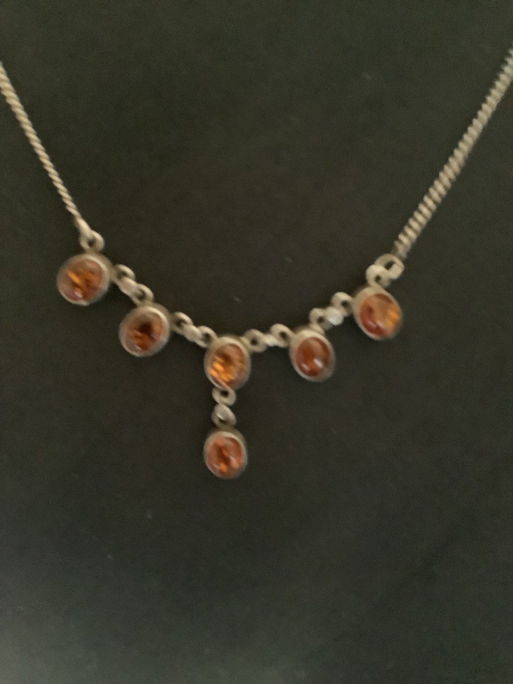 A fine silver chain necklace featuring six bezel-set oval cognac amber cabochons arranged in a central drop configuration. View III
